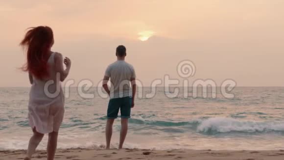 年轻的一对夫妇在海边欣赏日落视频的预览图