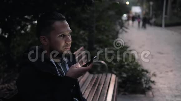 休闲快乐的人坐在公园的长凳上游客使用语音识别人工语音辅助音频视频的预览图