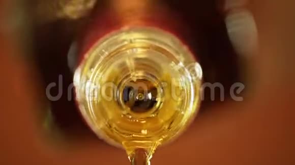 在棕色橙色背景下从瓶子里倒入威士忌一杯朗姆酒视频的预览图