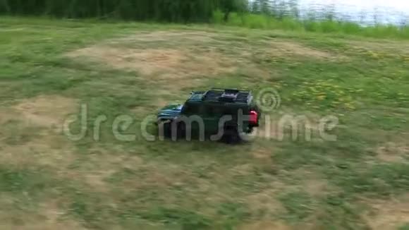无线电控制汽车在绿草地上行驶在美丽的夏日在湖边赛车瑞典视频的预览图