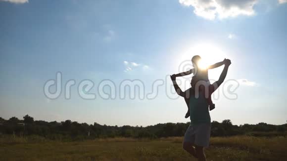 日落时分父亲和儿子在田野上玩耍小男孩坐在爸爸的肩膀上走在美丽的视频的预览图