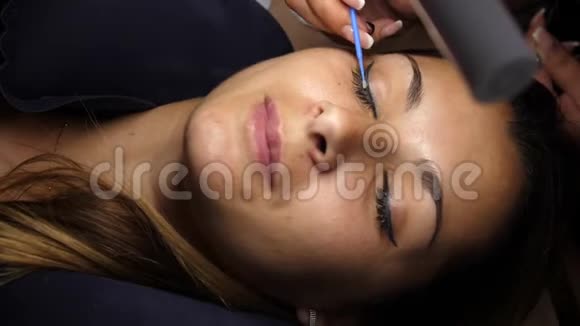 去除旧睫毛美容师用镊子取下睫毛女孩躺在灯下的手术上视频的预览图