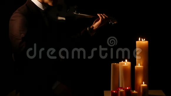 关闭小提琴演奏者在黑色背景下用蜡烛演奏乐器视频的预览图