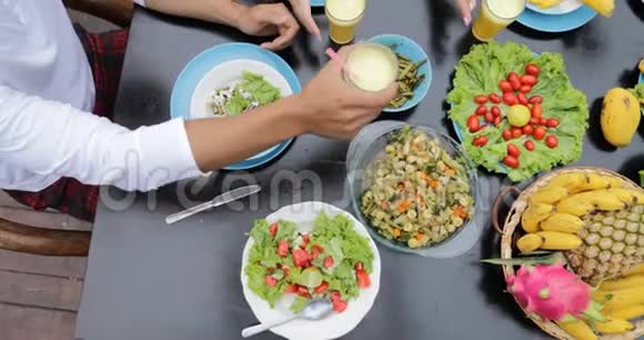 人们夹汁眼镜带热带水果菜肴的餐桌和健康的沙拉顶角观景朋友视频的预览图