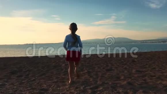 少年女孩白天在海滩上跑步小女孩在海上行走视频的预览图