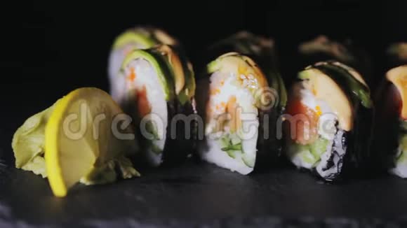 寿司配三文鱼片和新鲜黄瓜在黑石板上吃寿司特写视频的预览图