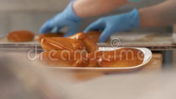 面包师把烤饼从托盘上放在盘子上放在厨房面包房附近视频的预览图