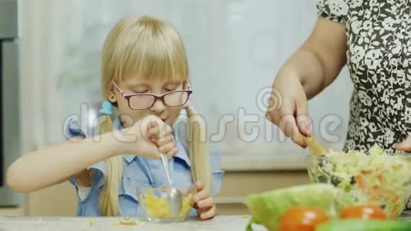 一个有趣的女孩从一个大碗里吃沙拉在她祖母旁边做沙拉去看望我心爱的祖母视频的预览图
