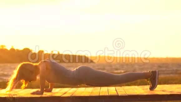 神奇日出时穿着紧身衣的年轻女子在海面上的海滩上练习瑜伽视频的预览图