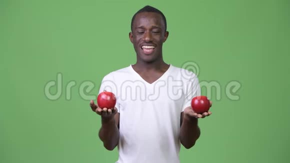 年轻快乐的非洲男人笑着吃红苹果视频的预览图