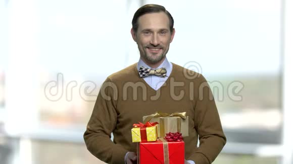 优雅的男人在模糊的背景上带着礼品盒视频的预览图