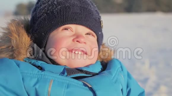 冬天特写户外可爱梦幻的小男孩肖像快乐的小男孩在雪地里玩耍户外视频的预览图