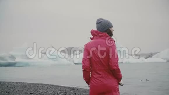 在冰泻湖散步的年轻迷人女子的后景一个人在冰岛探索著名的风景视频的预览图