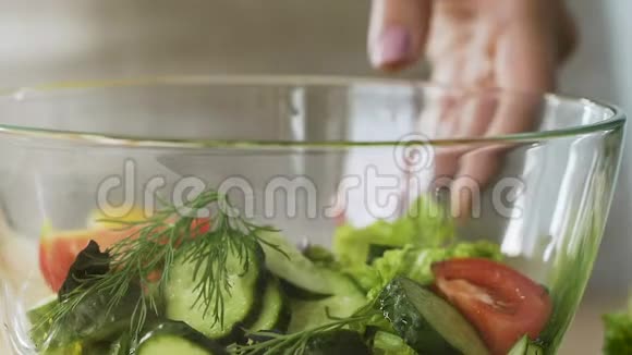 女性在蔬菜维生素沙拉中加入柠檬汁调味鲜餐视频的预览图