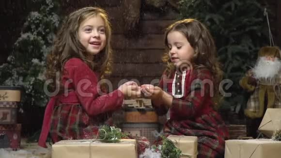 可爱的姐姐们并排坐在一个有圣诞礼物的房间里雪动作缓慢视频的预览图