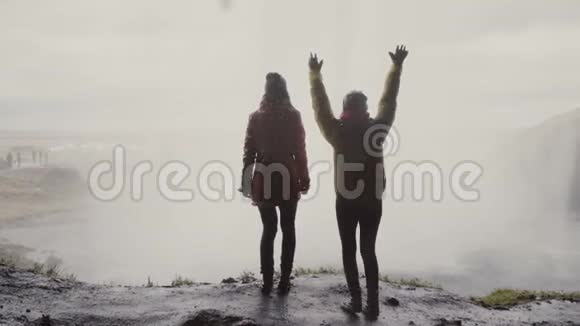 冰岛Gljufrabui瀑布附近两名快乐女游客的后景女人在眼前跳跃着欢乐视频的预览图