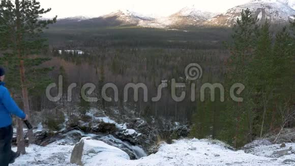 一个穿着运动服的男人站在山上的一个高处欣赏着美丽的景色他看着群山视频的预览图