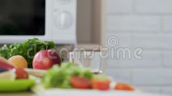 穿绿色连衣裙的女孩从桌子上拿苹果有机和健康的零食维生素视频的预览图