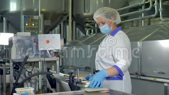 一位戴着塑料帽和口罩的工厂操作员检查奶酪包装4K视频的预览图
