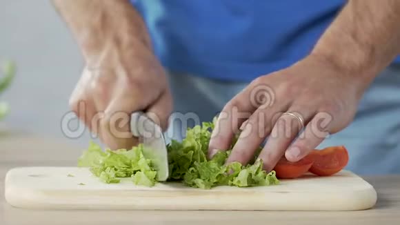 男人在家切绿莴苣和西红柿准备健康的家庭晚餐视频的预览图