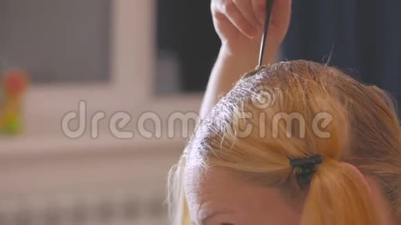 一个女人在家里用刷子刷上漂白油使她的发根变亮视频的预览图
