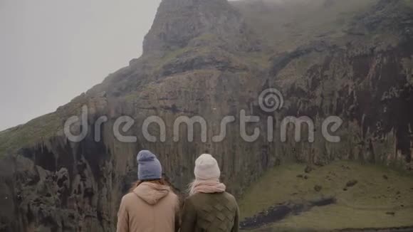 两个时髦的女人在岛上散步的后景游客在青山上寻找探索冰岛视频的预览图