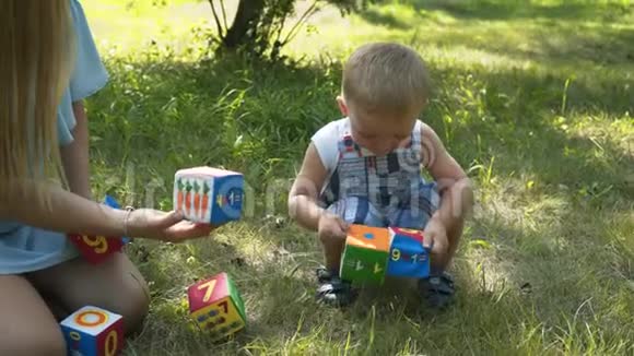 妈妈和她的儿子一起玩一个漂亮的小男孩看起来玩玩具浅皮肤蓝眼睛金发微笑的概念视频的预览图