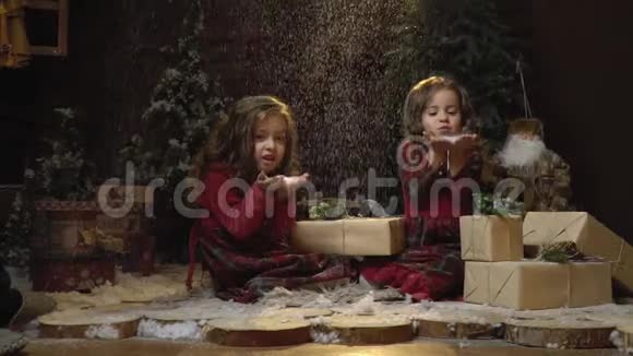穿着裙子的有趣的小女孩正坐在房间里的礼物中慢慢地她们会想起手中的雪视频的预览图