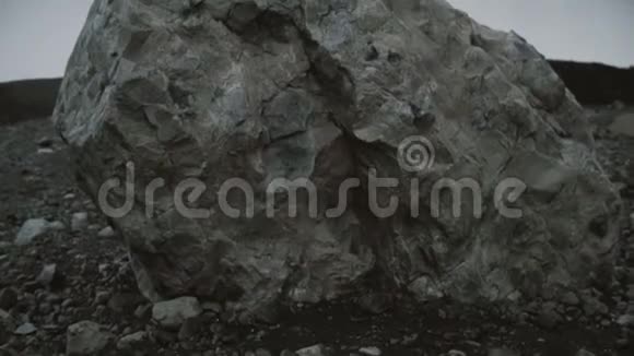 年轻男子独自坐在火山岩上观看冰岛冰泻湖的冰川视频的预览图