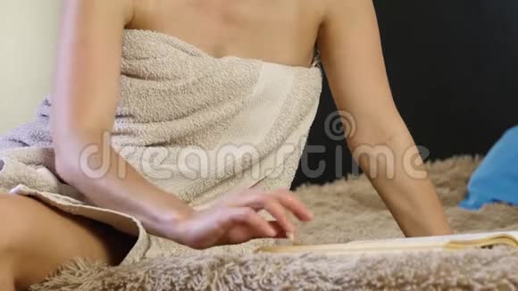 迷人的女人穿着浴巾看书美丽的年轻女孩舒适地躺在床上4K视频的预览图