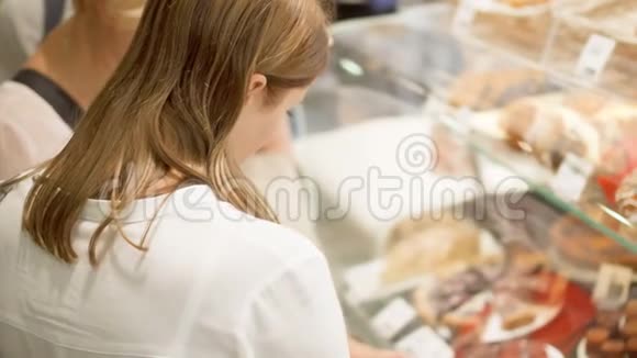 老妇人和她的女儿在商场购物站着看着玻璃盒选择糕点视频的预览图