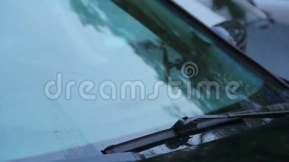 挡风玻璃雨刷在汽车前玻璃撕裂雨滴白天视频的预览图