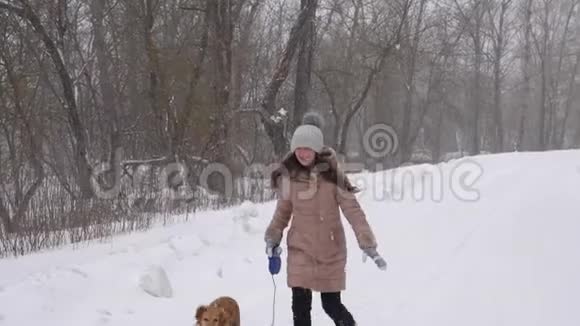 快乐的女孩带着猎狗在暴风雪中奔跑和微笑慢动作视频的预览图