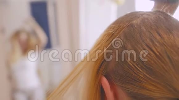 一个女人在家里用刷子刷上漂白油使她的发根变亮视频的预览图