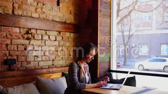 乔昆德女孩在大窗户附近的咖啡馆用笔记本电脑和盖伊聊天视频的预览图