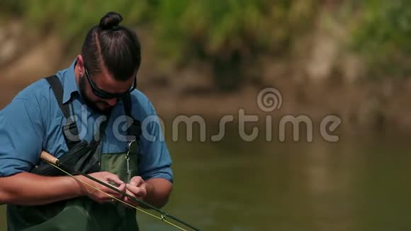 渔夫拿着一根鱼竿在河上钓鱼站在水里视频的预览图