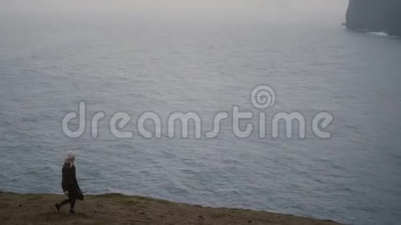 一个年轻的金发女人在雾天走在海边迷人的女性独自在山上徒步旅行视频的预览图