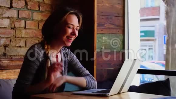漂亮的女人在咖啡馆用笔记本电脑打视频电话竖起大拇指吹吻视频的预览图