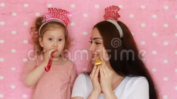 母女俩吹着党的角笑着玩着笑着庆祝着生日快乐一个女人和她的孩子视频的预览图
