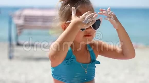 儿童涂抹防晒霜晒伤防晒霜防晒霜可爱的小女孩戴着太阳镜在一个视频的预览图
