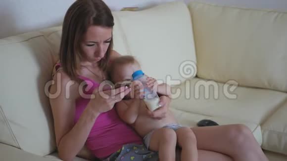 家庭技术母性和人的概念幸福的母亲小男孩躺在沙发上智能手机上视频的预览图