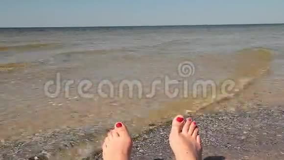 女人的脚带着红色的指甲在海滩上放松背景是海洋滚滚海浪视频的预览图