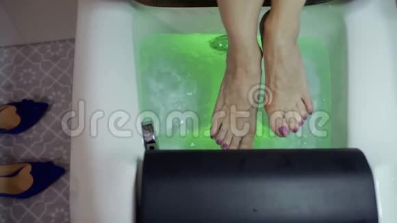 女人用泡泡和五颜六色的灯光在小浴中放松双脚视频的预览图