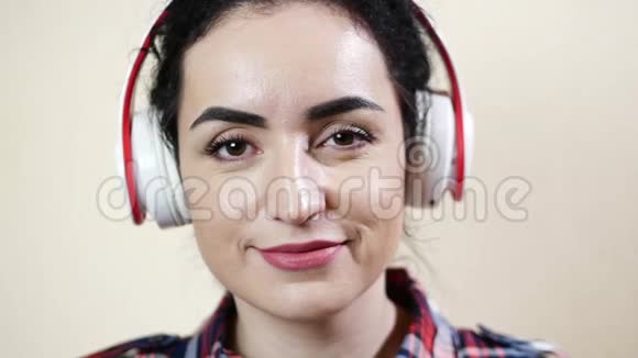 女美女带着耳机听音乐看着镜头眨眼视频的预览图