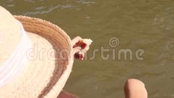 在泰国的大帽子里的旅游女孩从船上喂鱼4K慢运动视频的预览图