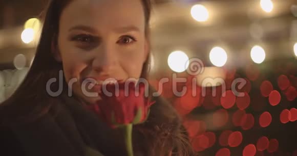 美丽的黑发女孩站在一个城市的红玫瑰视频的预览图