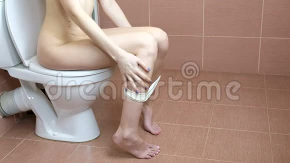 年轻女子坐在浴室的马桶上手里拿着卫生纸厕所的使用视频的预览图