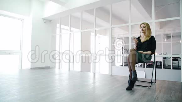 年轻女子坐在现代办公室里打电话视频的预览图