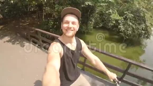 年轻的Hipser男子骑自行车和制作戈普罗自拍在公园高清视频的预览图