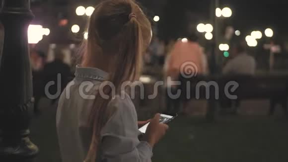 少女在城市里晚上使用智能手机视频的预览图